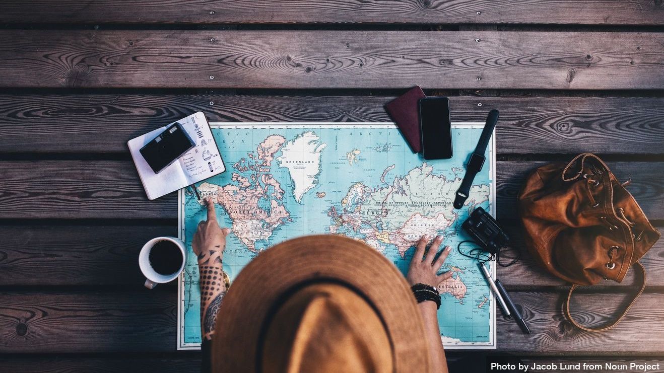 Tourist pointing at Alaska on the world map with her travel accessories around by Jacob Lund from Noun Project